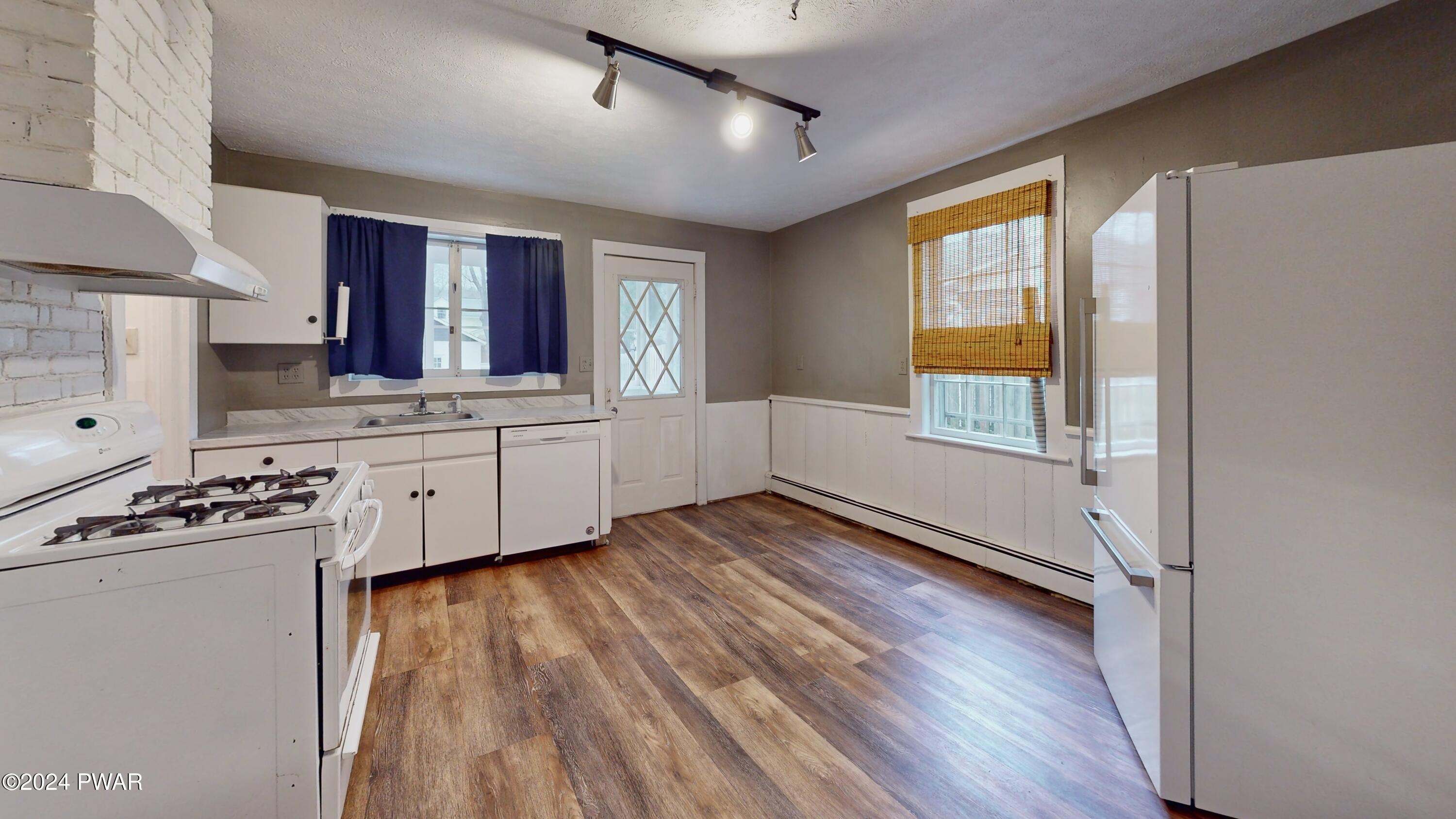 108 9th Street Milford, PA 18337 - Photo 12 of 38 a kitchen with granite countertop a stove a sink and white cabinets with wooden floor