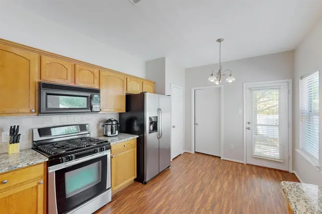 a kitchen with stainless steel appliances granite countertop a stove a sink dishwasher a refrigerator and a stove with wooden floor