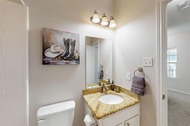 a bathroom with a granite countertop sink a toilet and mirror