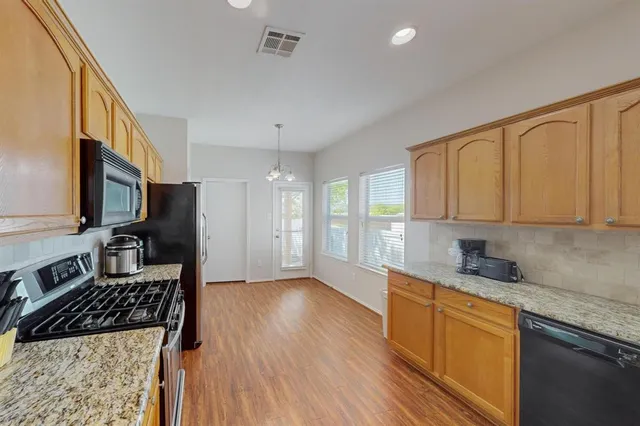 a kitchen with stainless steel appliances granite countertop a stove a sink and a refrigerator