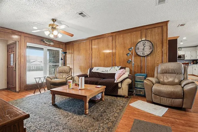 a kitchen with stainless steel appliances kitchen island granite countertop a refrigerator a sink a stove and white cabinets with wooden floor