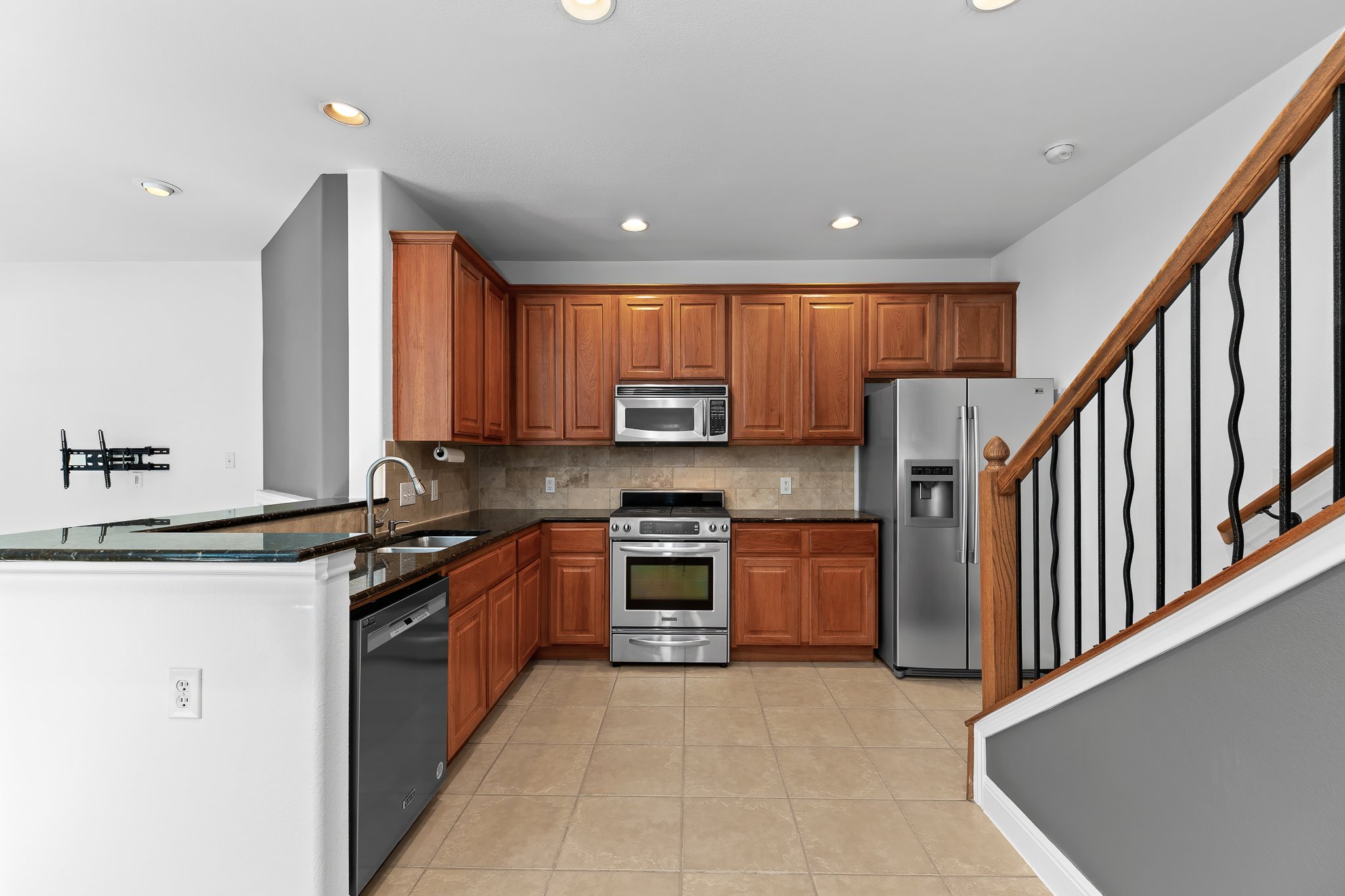 3406 Menchaca Road, Unit 28 Austin, TX 78704 - Photo 13 of 40 Kitchen featuring stainless steel appliances, wood finish cabinetry, dark stone counters, light tile patterned floors, and backsplash