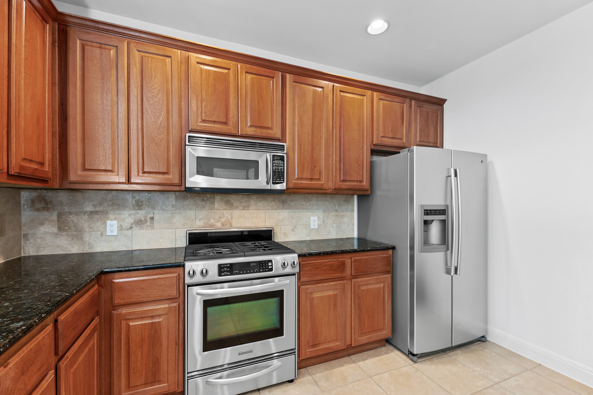 3406 Menchaca Road, Unit 28 Austin, TX 78704 - Photo 15 of 40 Kitchen featuring stainless steel appliances, wood finish cabinets, dark stone counters, decorative backsplash, and recessed lighting