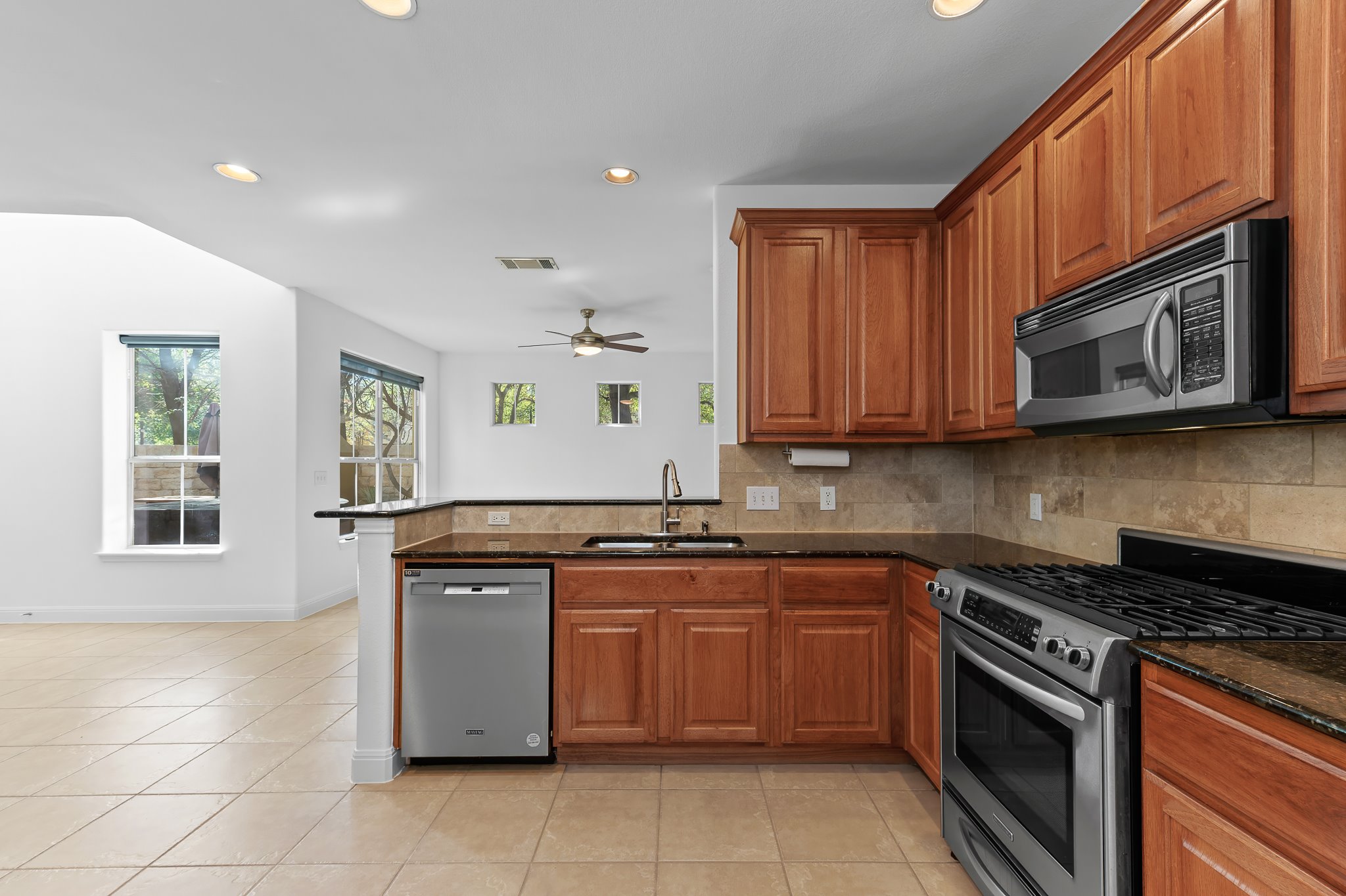 3406 Menchaca Road, Unit 28 Austin, TX 78704 - Photo 16 of 40 Kitchen featuring stainless steel appliances, dark stone countertops, wood finish cabinets, backsplash, and recessed lighting