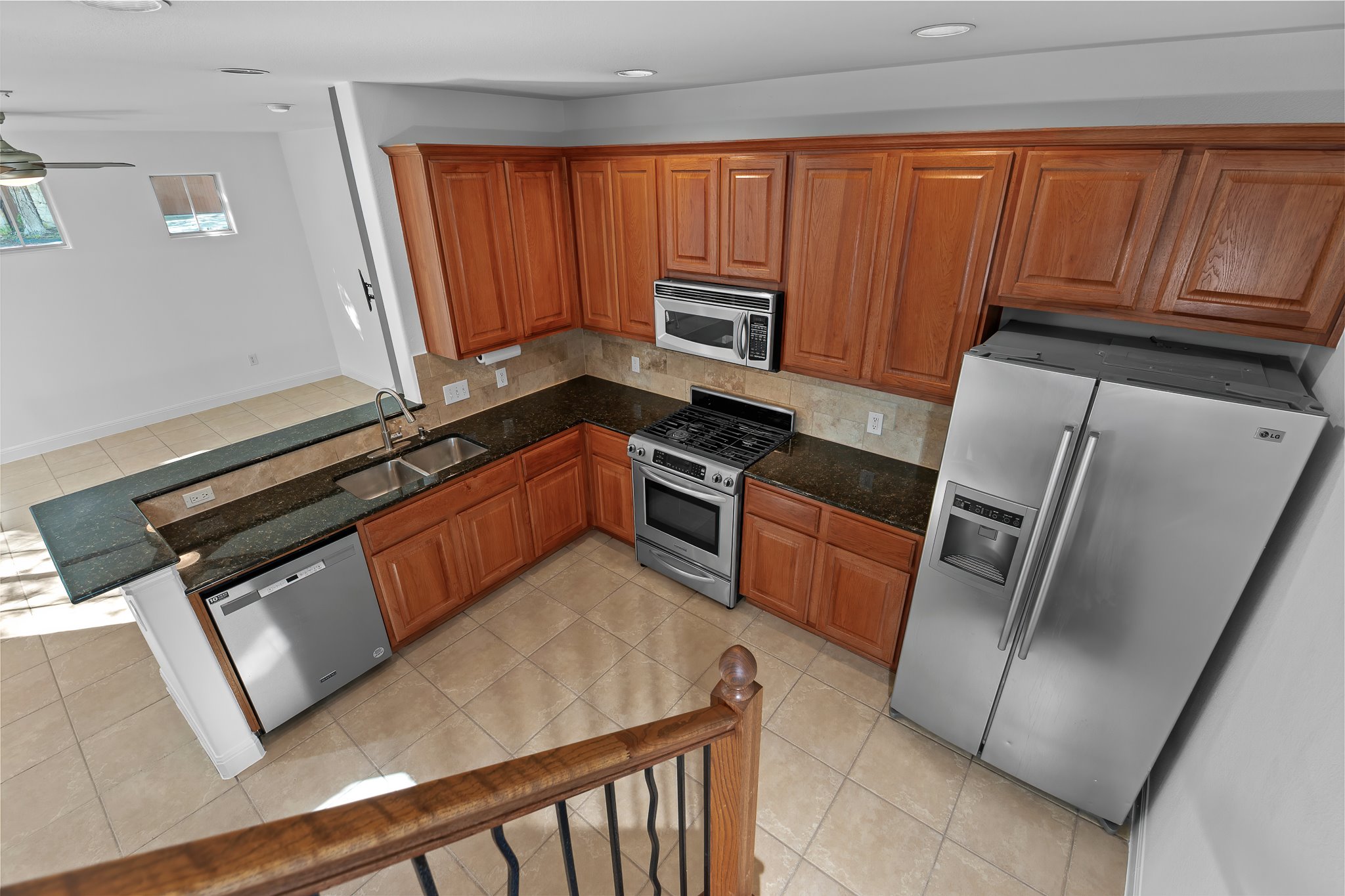 3406 Menchaca Road, Unit 28 Austin, TX 78704 - Photo 18 of 40 Kitchen with a peninsula, stainless steel appliances, light tile patterned floors, wood finish cabinetry, and dark stone counters