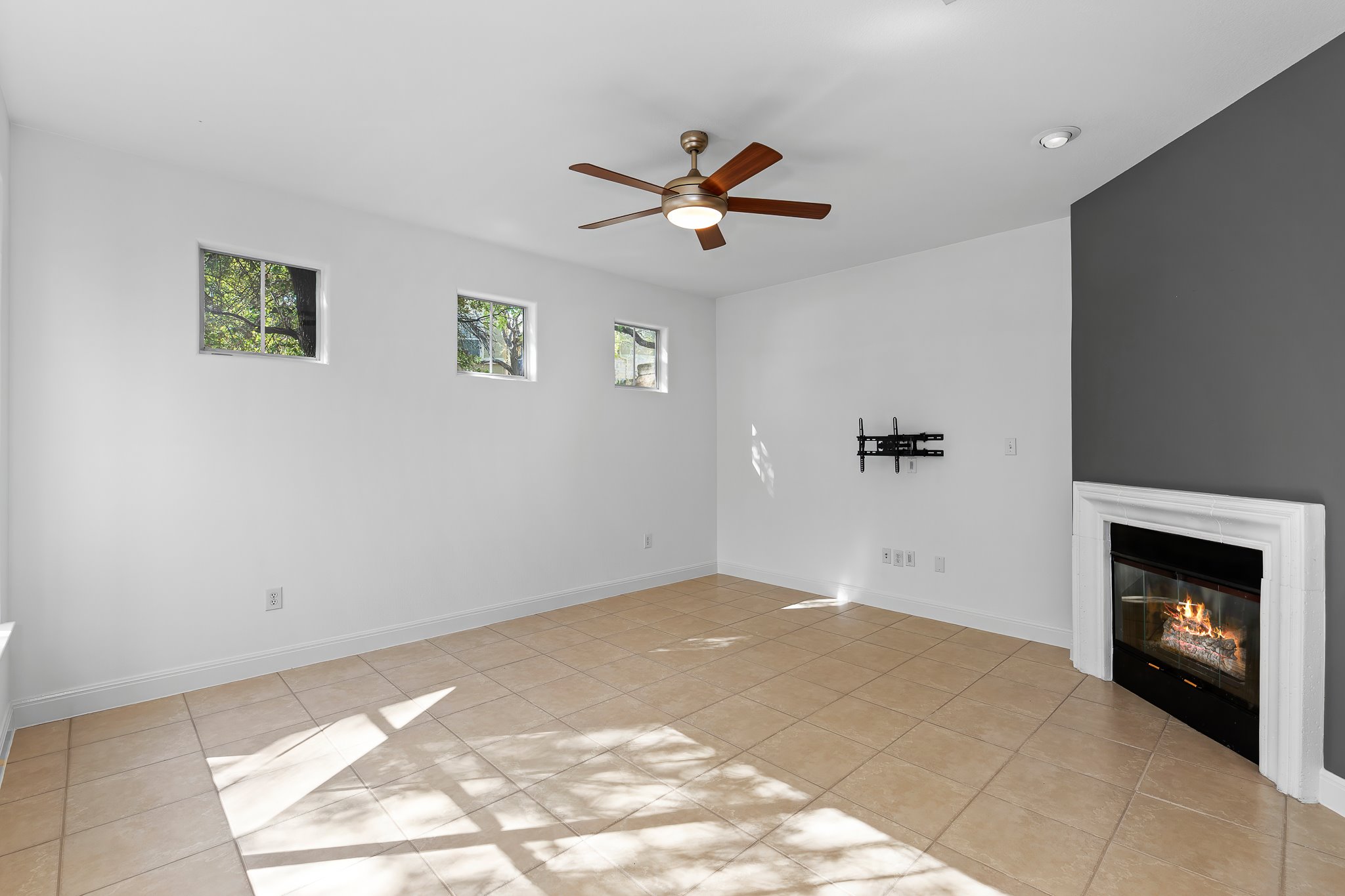 3406 Menchaca Road, Unit 28 Austin, TX 78704 - Photo 19 of 40 Unfurnished living room with ceiling fan, a glass covered fireplace, and light tile patterned flooring