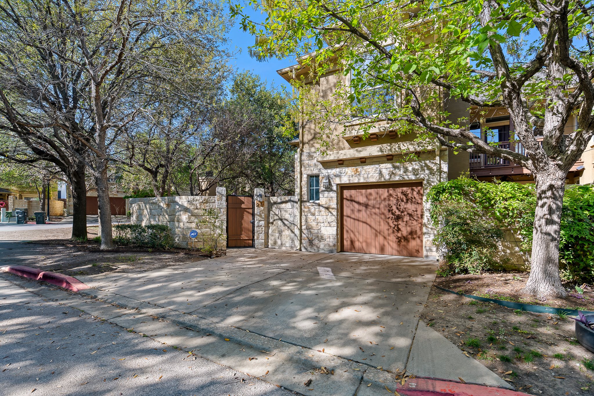 3406 Menchaca Road, Unit 28 Austin, TX 78704 - Photo 2 of 40 View of property exterior with concrete driveway, a garage, a gate, and stone siding