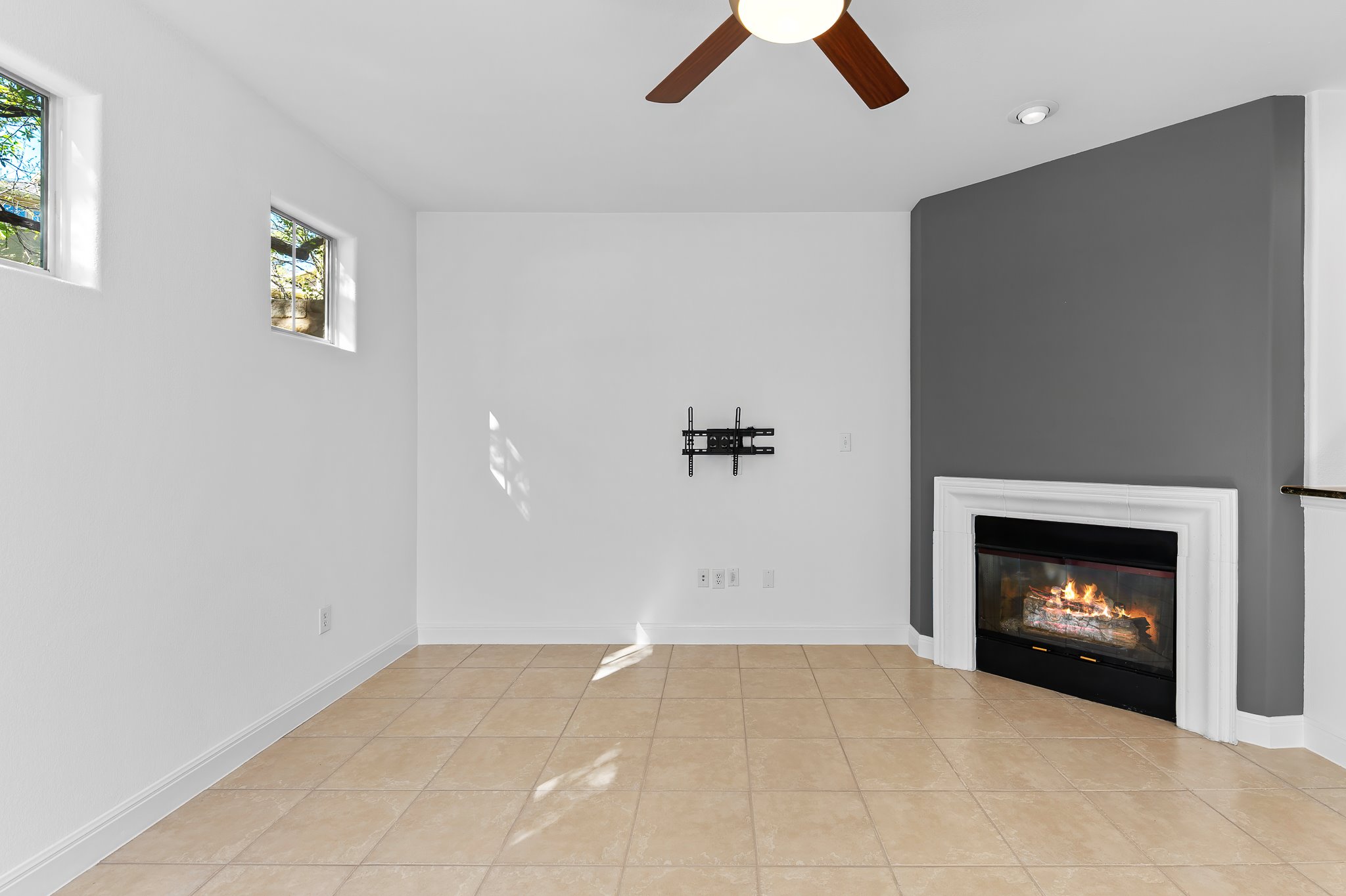 3406 Menchaca Road, Unit 28 Austin, TX 78704 - Photo 21 of 40 Unfurnished living room with ceiling fan, a glass covered fireplace, and light tile patterned floors