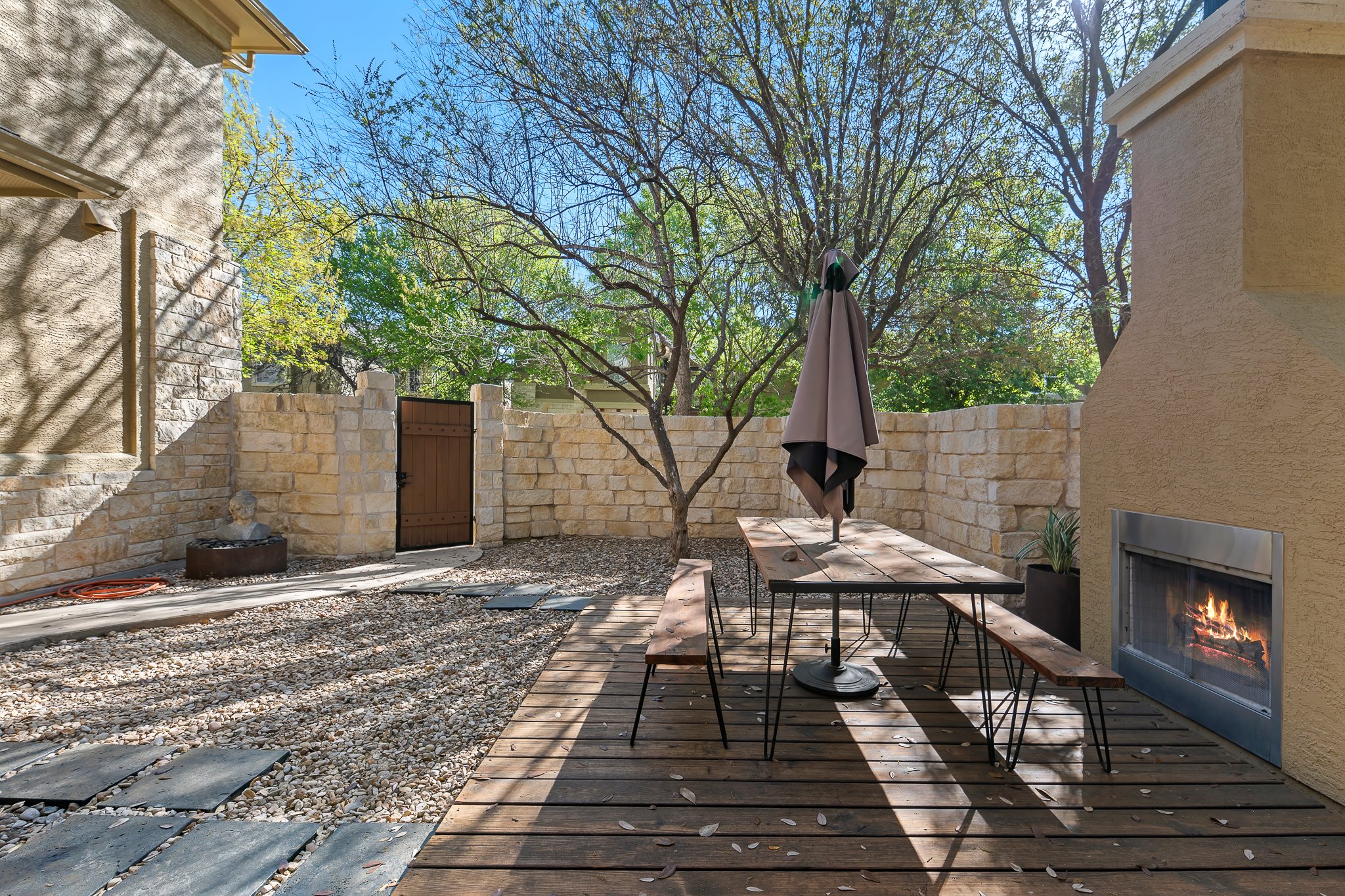 3406 Menchaca Road, Unit 28 Austin, TX 78704 - Photo 6 of 40 Deck with outdoor dining area, a gate, a fenced backyard, and a lit fireplace