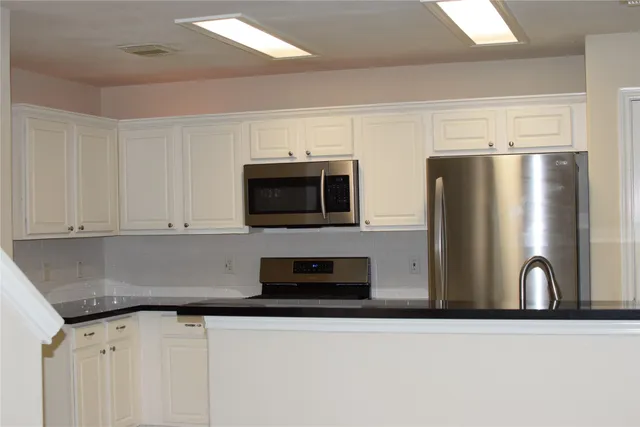 a kitchen with stainless steel appliances granite countertop a refrigerator a stove top oven