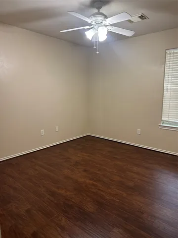 an empty room with wooden floor fan and window