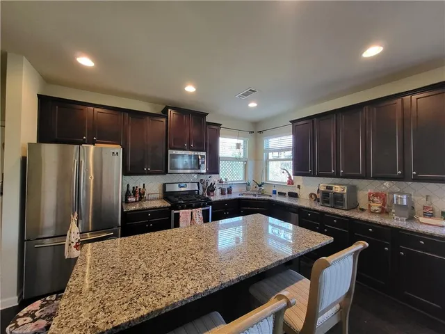 a kitchen with kitchen island granite countertop a sink refrigerator and cabinets