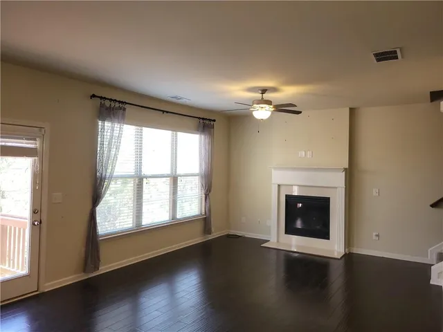 an empty room with wooden floor fireplace and windows