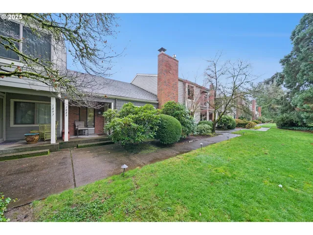 a view of a brick house with a big yard and large tree