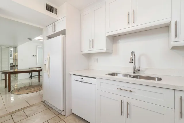 a kitchen with white cabinets and sink
