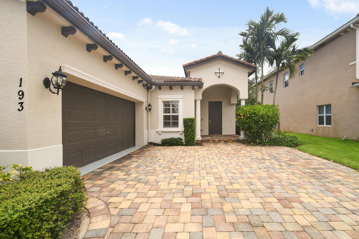 193 Porgee Rock Place Jupiter, FL 33458 - Photo 37 of 76 a view of a white house with a yard and potted plants