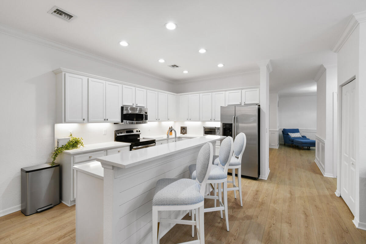 193 Porgee Rock Place Jupiter, FL 33458 - Photo 10 of 76 a kitchen with a refrigerator a stove top oven a sink dishwasher and white cabinets with wooden floor