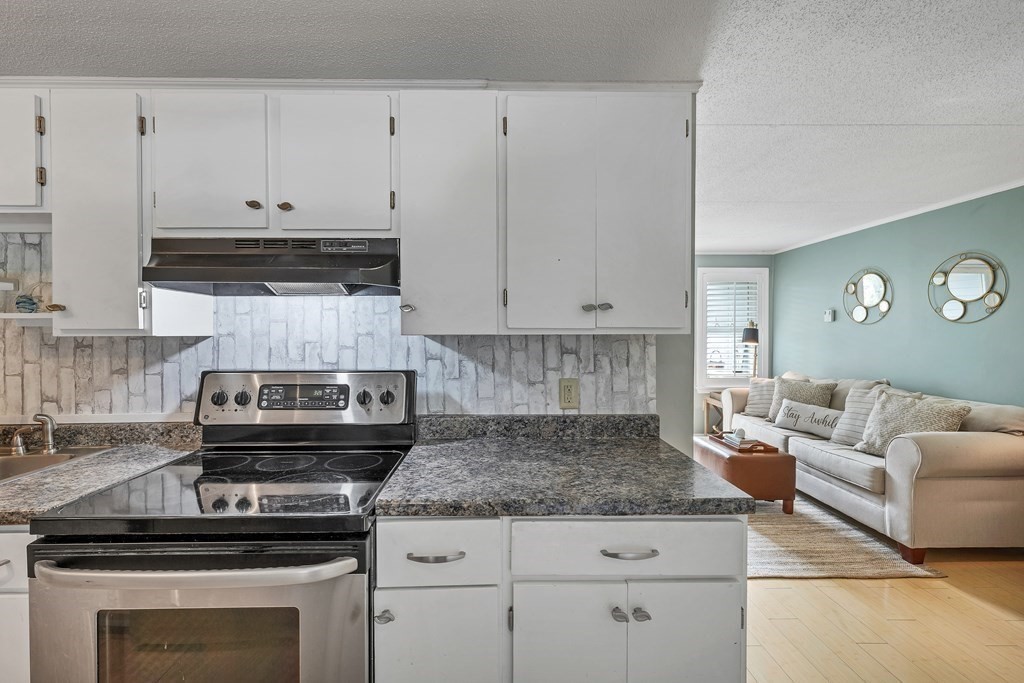 64 Esker Road, Unit 2 Hampton, NH 03842 - Photo 8 of 33 a kitchen with granite countertop a stove a sink and white cabinets