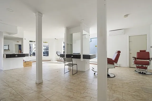 a living room with couches and kitchen view with wooden floor