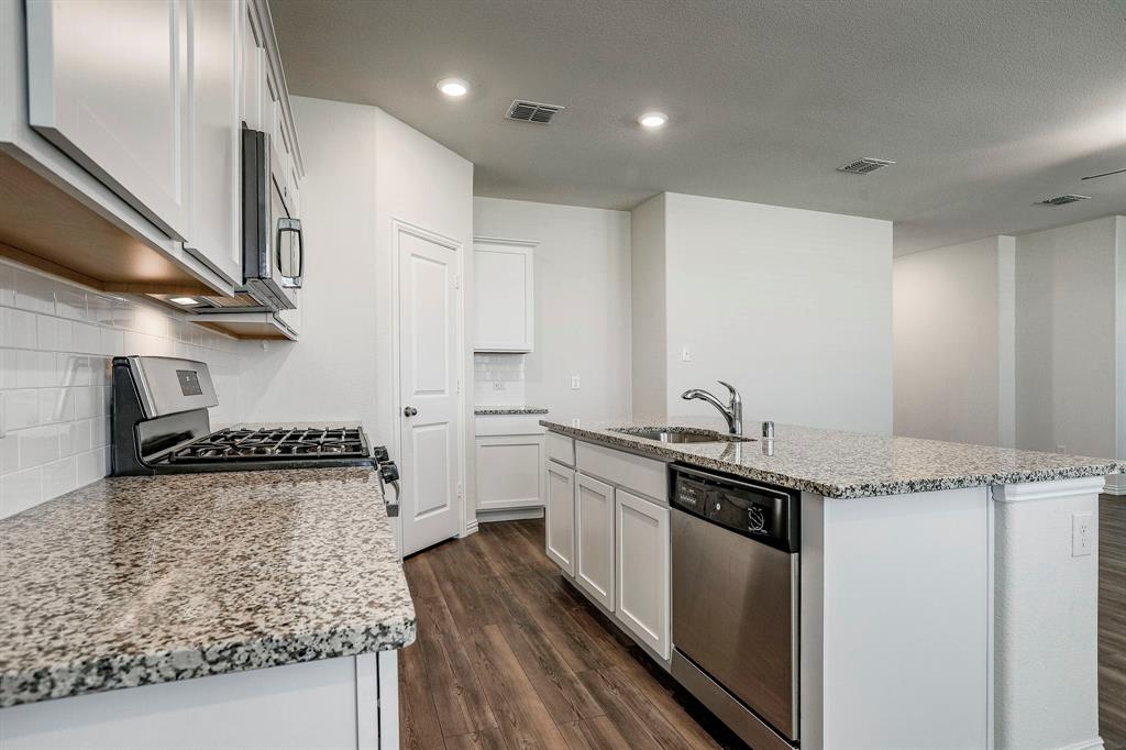 652 Ridgeback Trail Fort Worth, TX 76052 - Photo 8 of 20 Kitchen with sink, tasteful backsplash, white cabinetry, a center island with sink, and stainless steel appliances