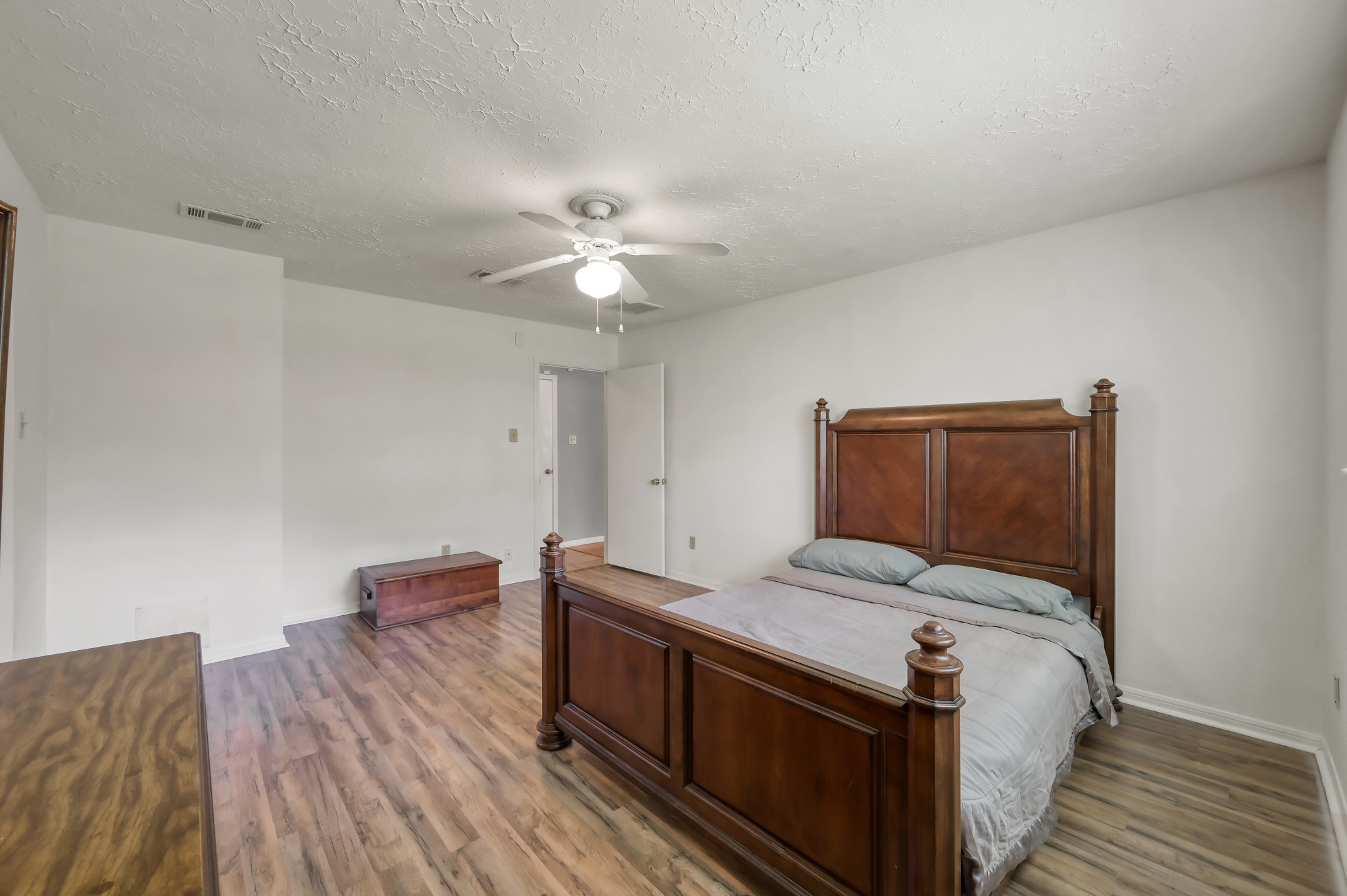 4314 Enchantedgate Drive Spring, TX 77373 - Photo 23 of 47 Spacious primary bedroom with a wooden floor, featuring a large bed and a ceiling fan, creating a comfortable and airy atmosphere.