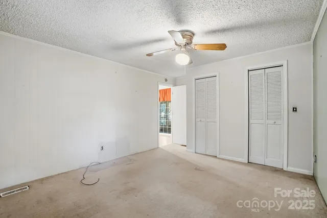 an empty room with windows and fan