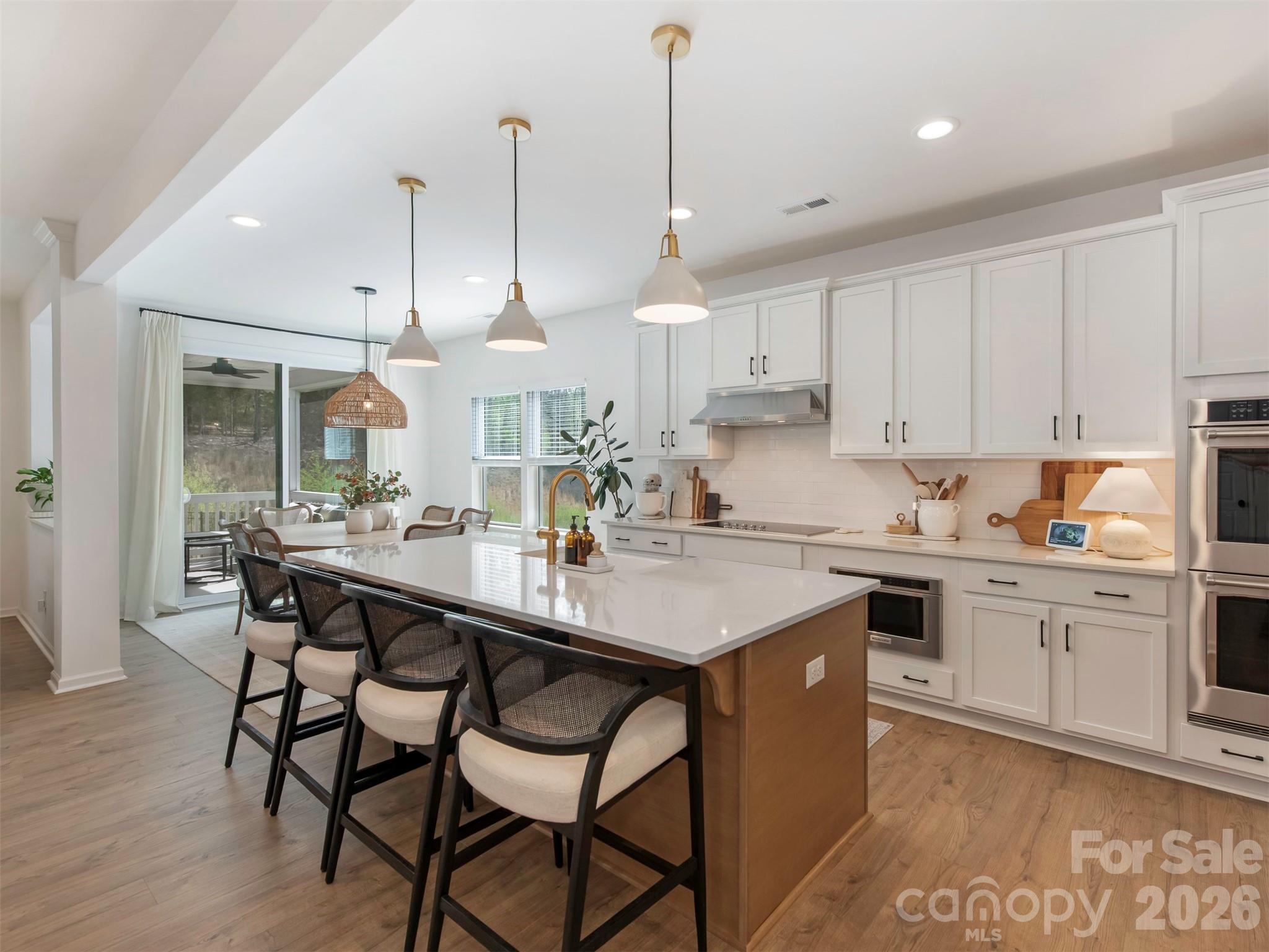 966 Scotch Meadows Loop Monroe, NC 28110 - Photo 11 of 48 a kitchen with stainless steel appliances granite countertop a sink a stove a dining table and chairs with wooden floor