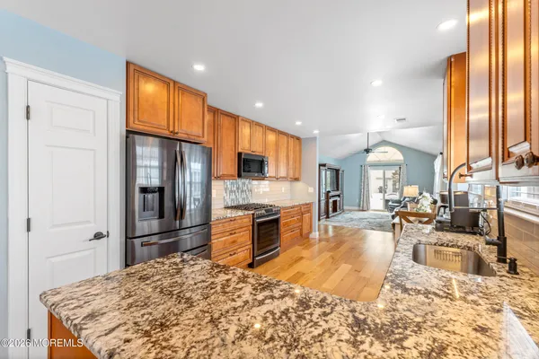 a large kitchen with stainless steel appliances kitchen island granite countertop a refrigerator oven a sink dishwasher with a dining table and chairs with wooden floor