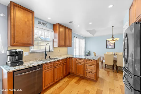 a kitchen with granite countertop wooden cabinets a sink a window and stainless steel appliances