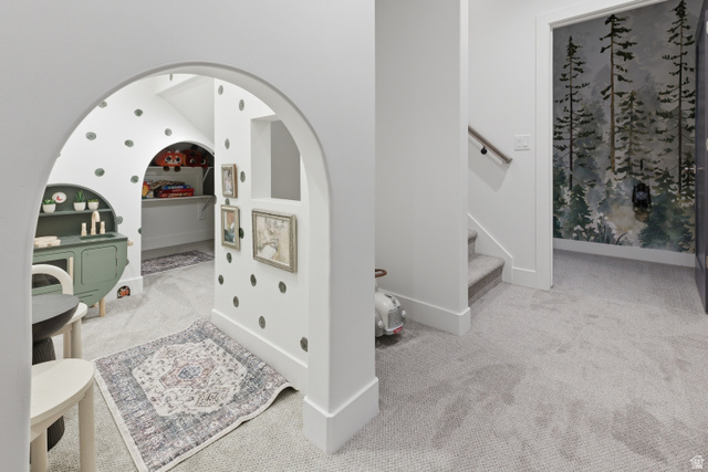 2559 West Aurora Avenue Mapleton, UT 84664 - Photo 38 of 60 Carpeted hallway featuring an arched entryway to a recessed area with built-in shelving, a second arched alcove with shelving, and a wall mural depicting a forest scene