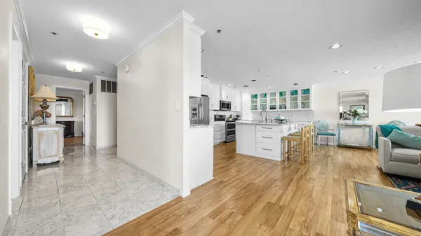 a kitchen with stainless steel appliances kitchen island granite countertop a stove a sink a refrigerator and white cabinets with wooden floor