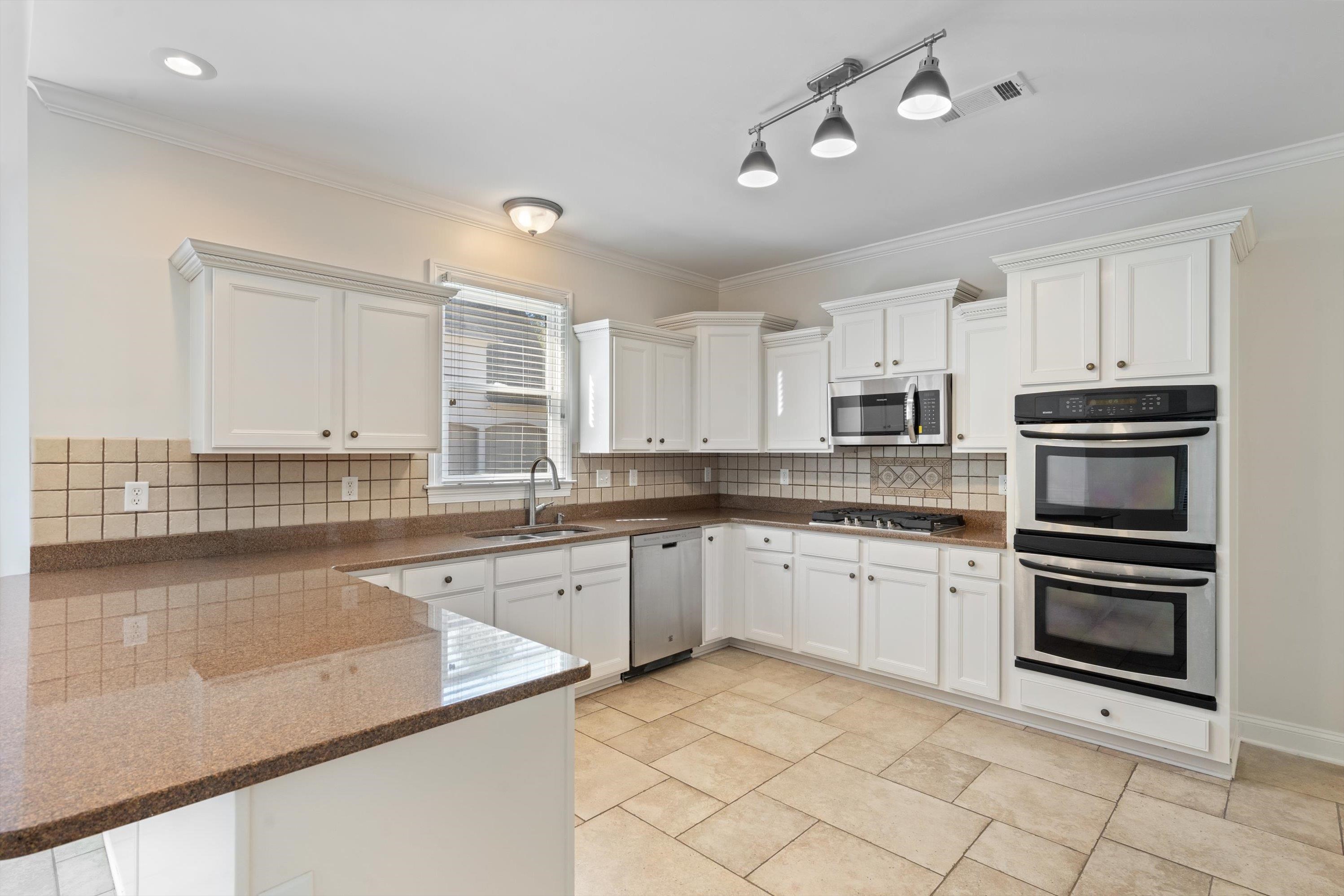 1710 Stillwind Lane Collierville, TN 38017 - Photo 11 of 40 Kitchen with freshly painted white cabinets, gas cooking, double ovens and stone countertops