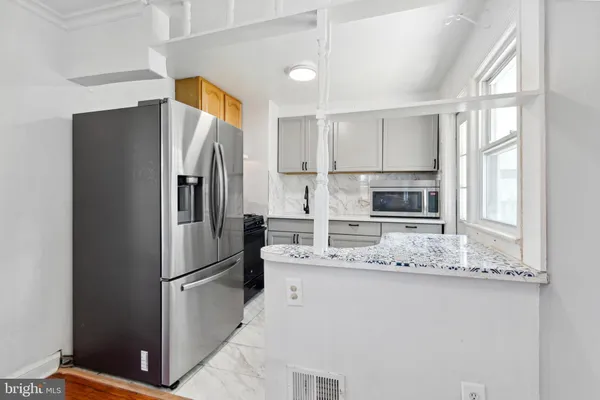 a kitchen with stainless steel appliances granite countertop a refrigerator a stove a sink and a granite counter tops with white cabinets