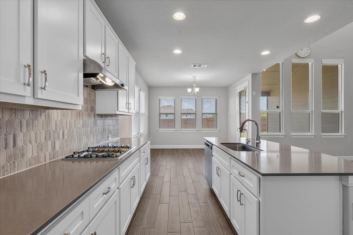 109 Rocky River Road Georgetown, TX 78628 - Photo 12 of 37 Modern kitchen with white cabinetry and a central island seamlessly flows into a bright dining area.