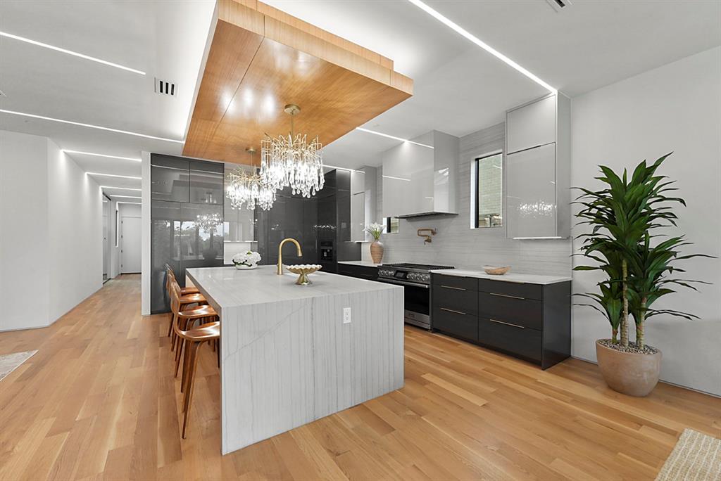 9457 Waterview Road Dallas, TX 75218 - Photo 15 of 25 Gourmet kitchen featuring a waterfall island with integrated seating, dual crystal chandeliers, and a wood-finish ceiling accent