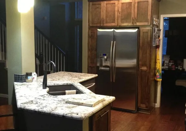 a kitchen with kitchen island granite countertop a refrigerator stove and sink