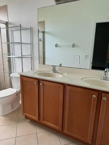a bathroom with a granite countertop sink a toilet a mirror and vanity