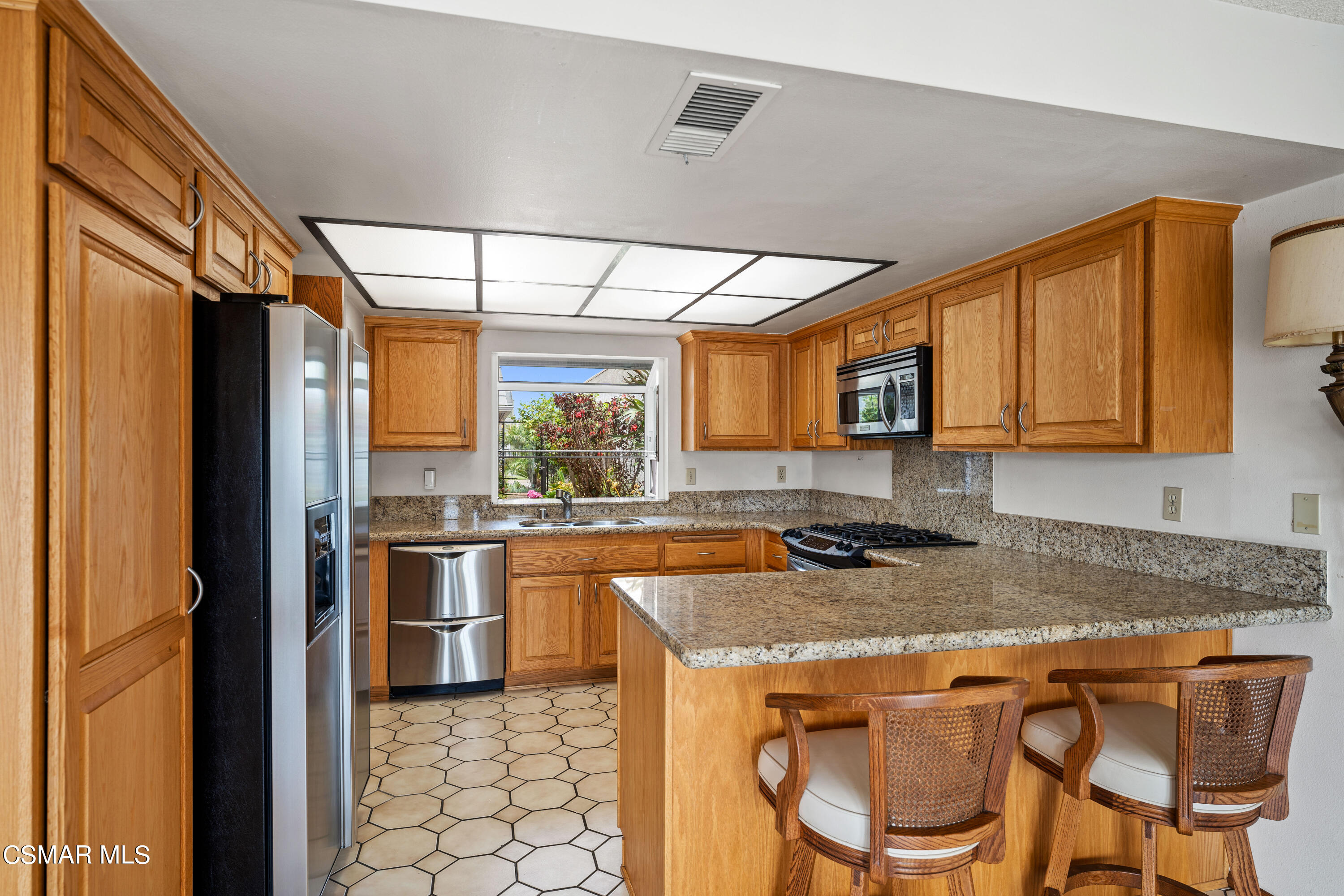 4512 Falkirk Bay Oxnard, CA 93035 - Photo 14 of 40 a kitchen with stainless steel appliances granite countertop a stove a refrigerator a sink dishwasher with a dining table and chairs