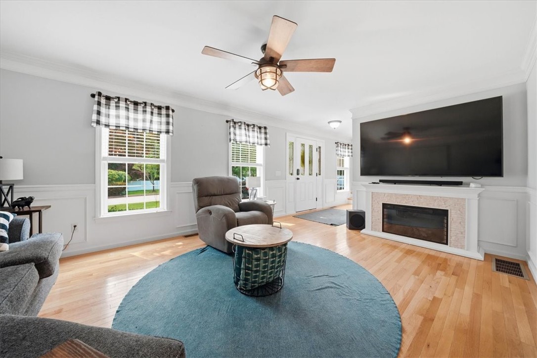 26 Davis Circle Warwick, RI 02886 - Photo 9 of 50 Designed for comfort and connection, the expansive living room features rich hardwood flooring, detailed millwork, abundant natural light, and a stylish electric fireplace that serves as a beautiful focal point.