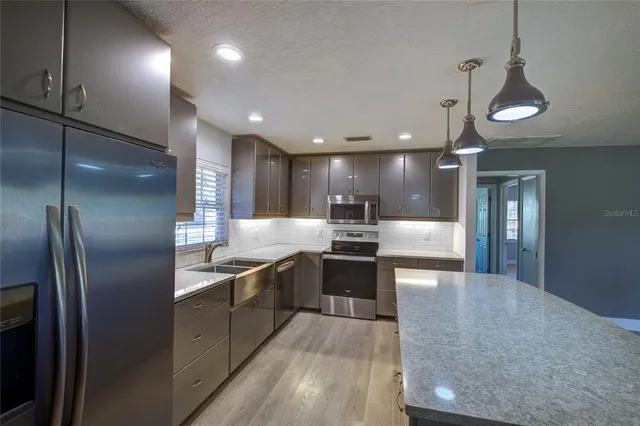 a large kitchen with stainless steel appliances kitchen island a large counter top and a refrigerator