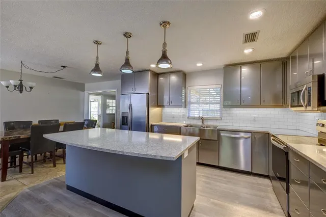 a large kitchen with kitchen island a sink a counter space and stainless steel appliances