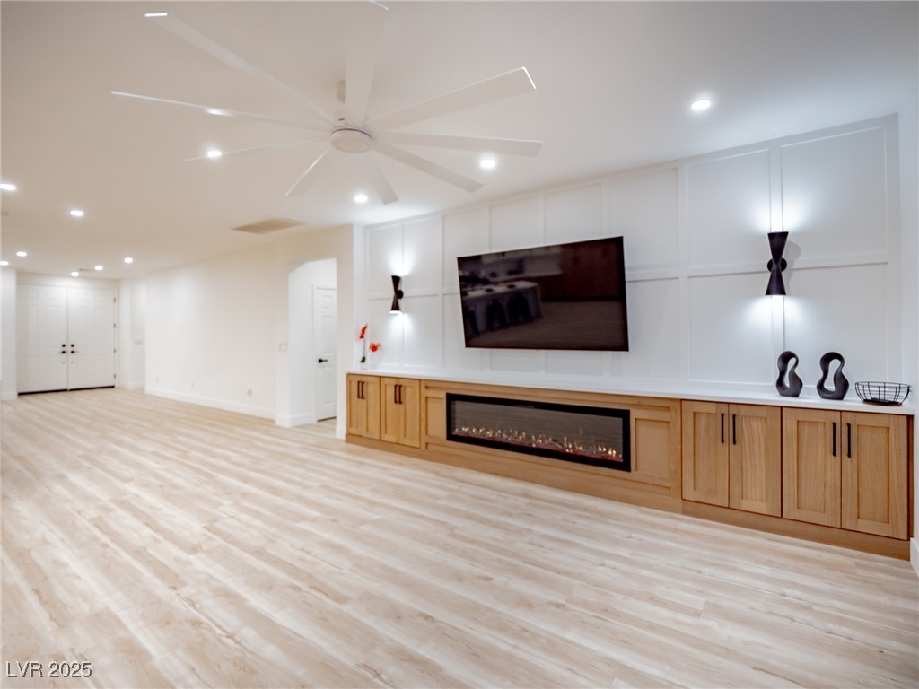 7870 Midnight Ride Street Las Vegas, NV 89131 - Photo 26 of 69 Unfurnished living room with recessed lighting, light wood-style floors, a glass covered fireplace, a ceiling fan, and a decorative wall