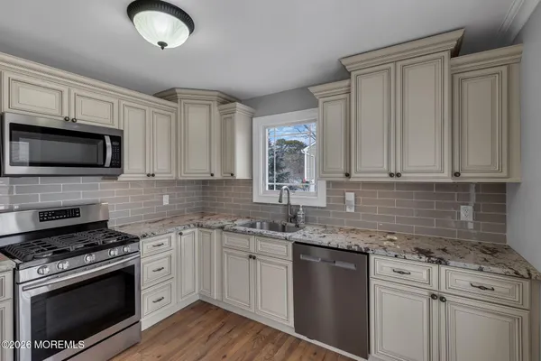 a kitchen with granite countertop a sink stainless steel appliances and white cabinets