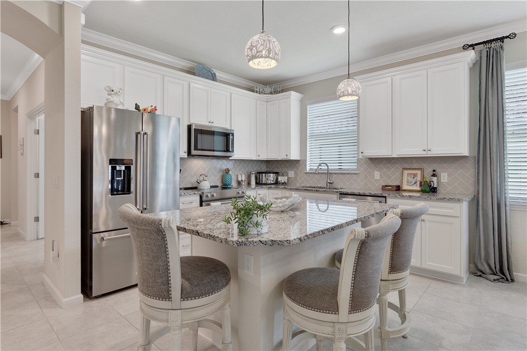 5122 Unity Square Vero Beach, FL 32967 - Photo 6 of 33 a kitchen with stainless steel appliances granite countertop a sink a stove a refrigerator with a dining table and chairs