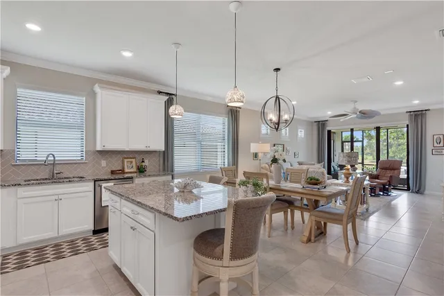 a kitchen with stainless steel appliances granite countertop a dining table chairs refrigerator and cabinets