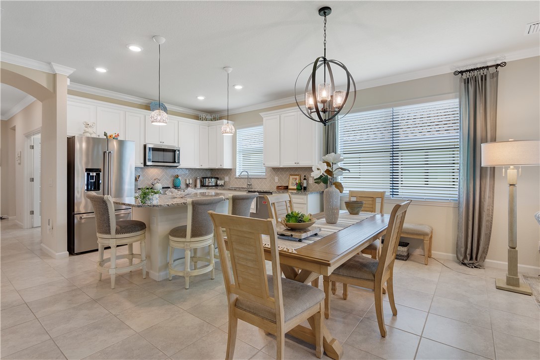 5122 Unity Square Vero Beach, FL 32967 - Photo 9 of 33 a kitchen with stainless steel appliances granite countertop a dining table chairs refrigerator and cabinets