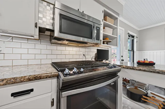 a kitchen with granite countertop a stove and a microwave
