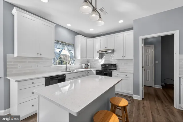 a kitchen with a sink a stove a refrigerator and white cabinets with wooden floor