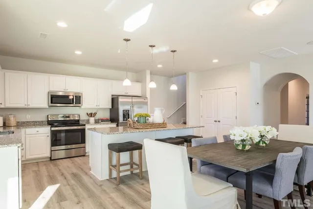 a kitchen with stainless steel appliances kitchen island granite countertop a stove a sink a refrigerator and a dining table