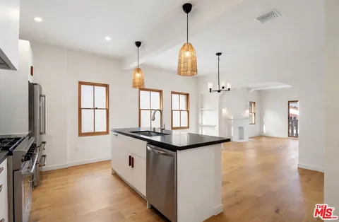 a kitchen with stainless steel appliances granite countertop a refrigerator a stove a microwave and a wooden floor